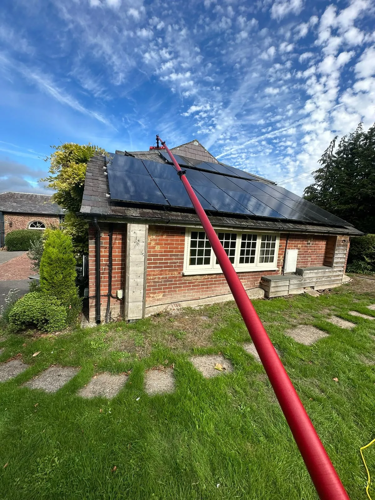 A Clean Team Sussex water-fed pole cleaning the solar panels on a brick house roof