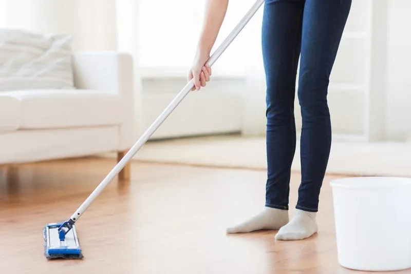 Mopping a wooden floor in a bright, freshly cleaned living room